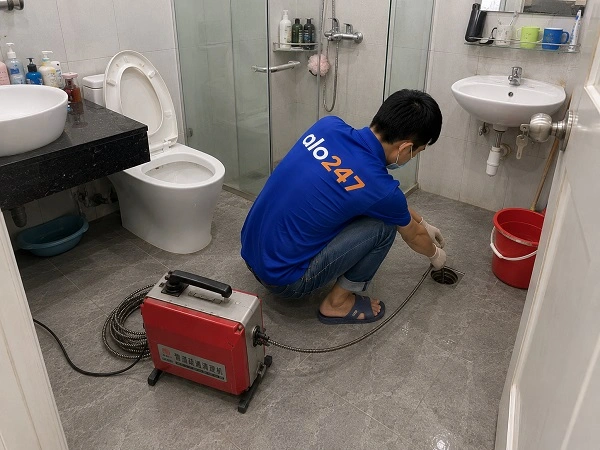 Thợ alo247 đang sử dụng máy lò xo để thông tắc cống sàn nhà vệ sinh tại Tây Hồ