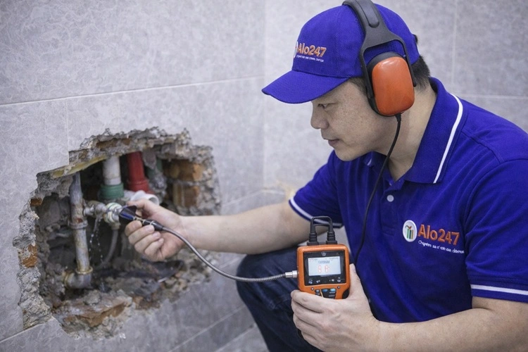 thợ alo247 đang kiểm tra đường ống nước bị rò rỉ âm tường bằng máy siêu âm