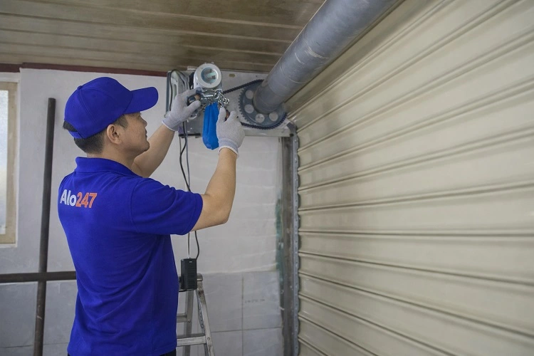 Kỹ thuật viên đang thao tác sửa chữa cửa cuốn