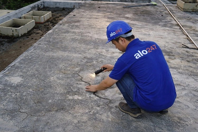 Thợ kiểm tra mái bê tông bị nứt gây thấm dột