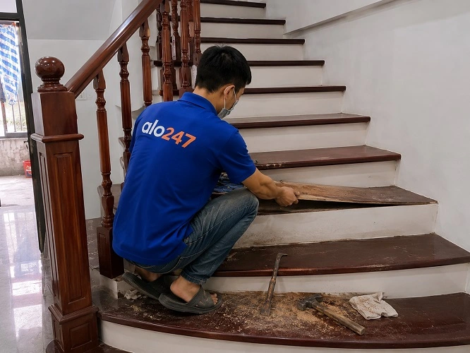 Thợ alo247 đang sửa chữa mặt bậc cầu thang gỗ