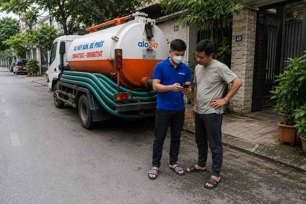 Thợ alo247 giải thích quy trình hút bể phốt bằng xe chân không cho khách hàng tại Vật Lại