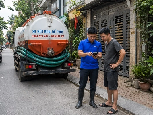 Thợ giải thích phương án hút bể phốt bằng xe chân không cho khách hàng tại Hát Môn
