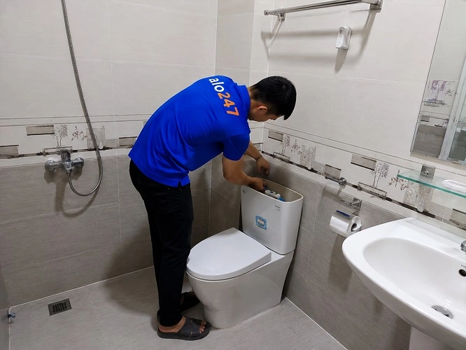 Thợ alo247 đang sửa bồn cầu hỏng phao tự động bị rò rỉ nước