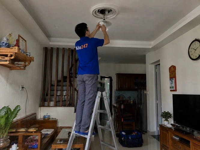 Thợ alo247 đang thay bóng đèn phòng khách