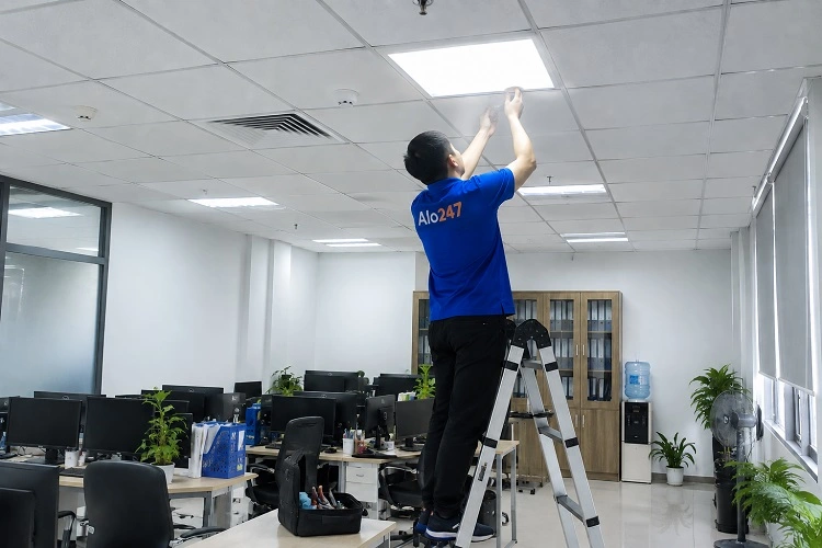 Thợ alo247 đang thay bóng đèn tại văn phòng