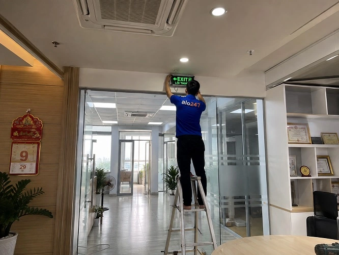 Thợ alo247 đang thay đèn thoát hiểm