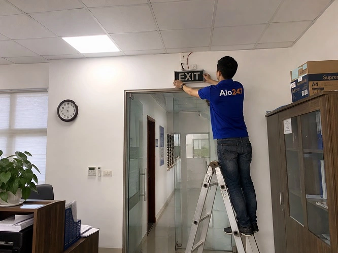 Thợ alo247 đang thay đèn thoát hiểm