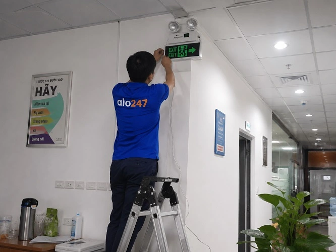 thợ alo247 đang lắp đèn chỉ hướng thoát hiểm