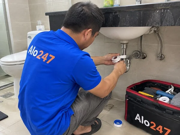 Thợ Alo247 đang sửa chữa xi phông bồn rửa bị rò nước