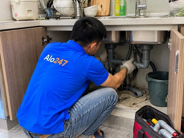 Thợ Alo247 đang sửa đường ống thoát nước bồn rửa bát bị tắc